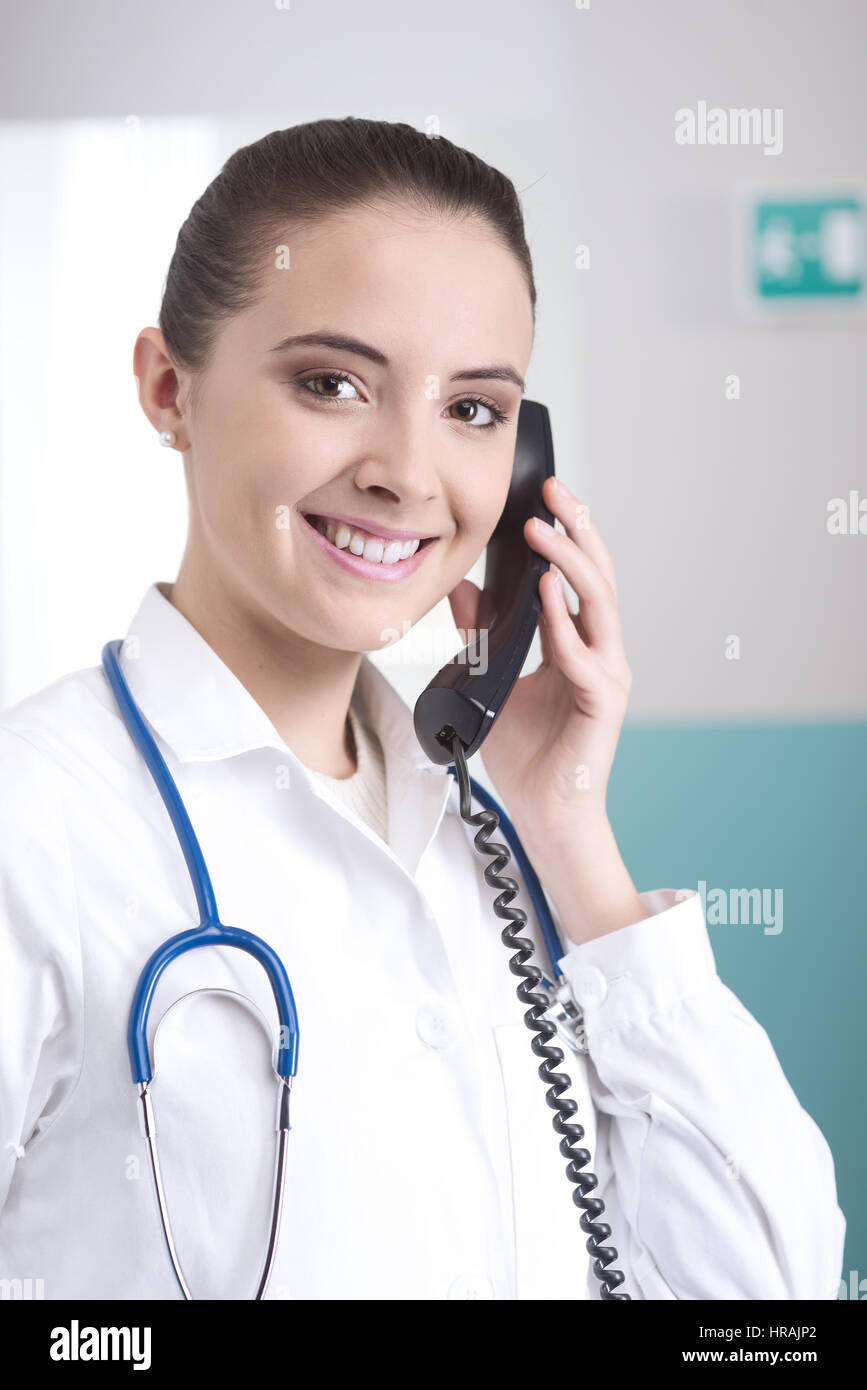 Young female doctor talking on the phone and smiling Stock Photo - Alamy
