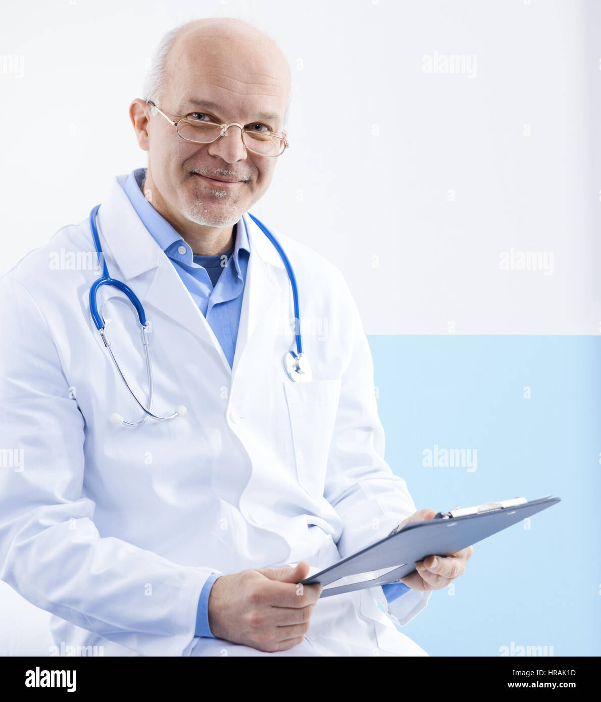 Friendly confident doctor sitting on a medical examination bed Stock