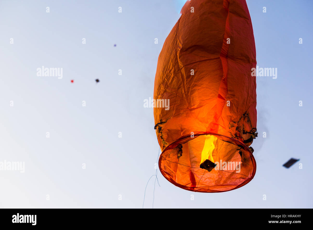 Burnt damaged sky lantern against a blue sky filled with kites in Jaipur on Makar Sankranti Stock Photo