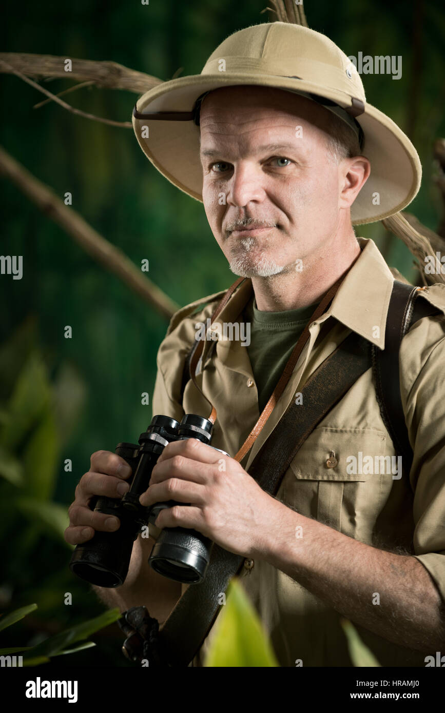 Smiling explorer in colonial style clothing holding binoculars and looking at camera. Stock Photo