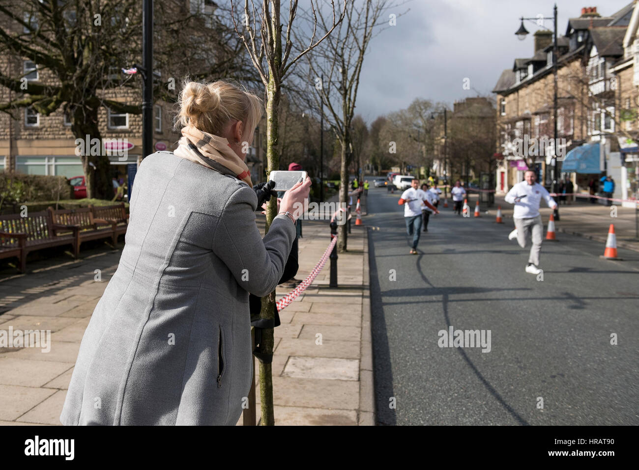 The Grove, Ilkley, West Yorkshire, England, UK. 28th Feb, 2017. A lady takes a photo of competitors running in the traditional, annual Ilkley Rotary Pancake Race on Shrove Tuesday. Credit: Ian Lamond/Alamy Live News Stock Photo