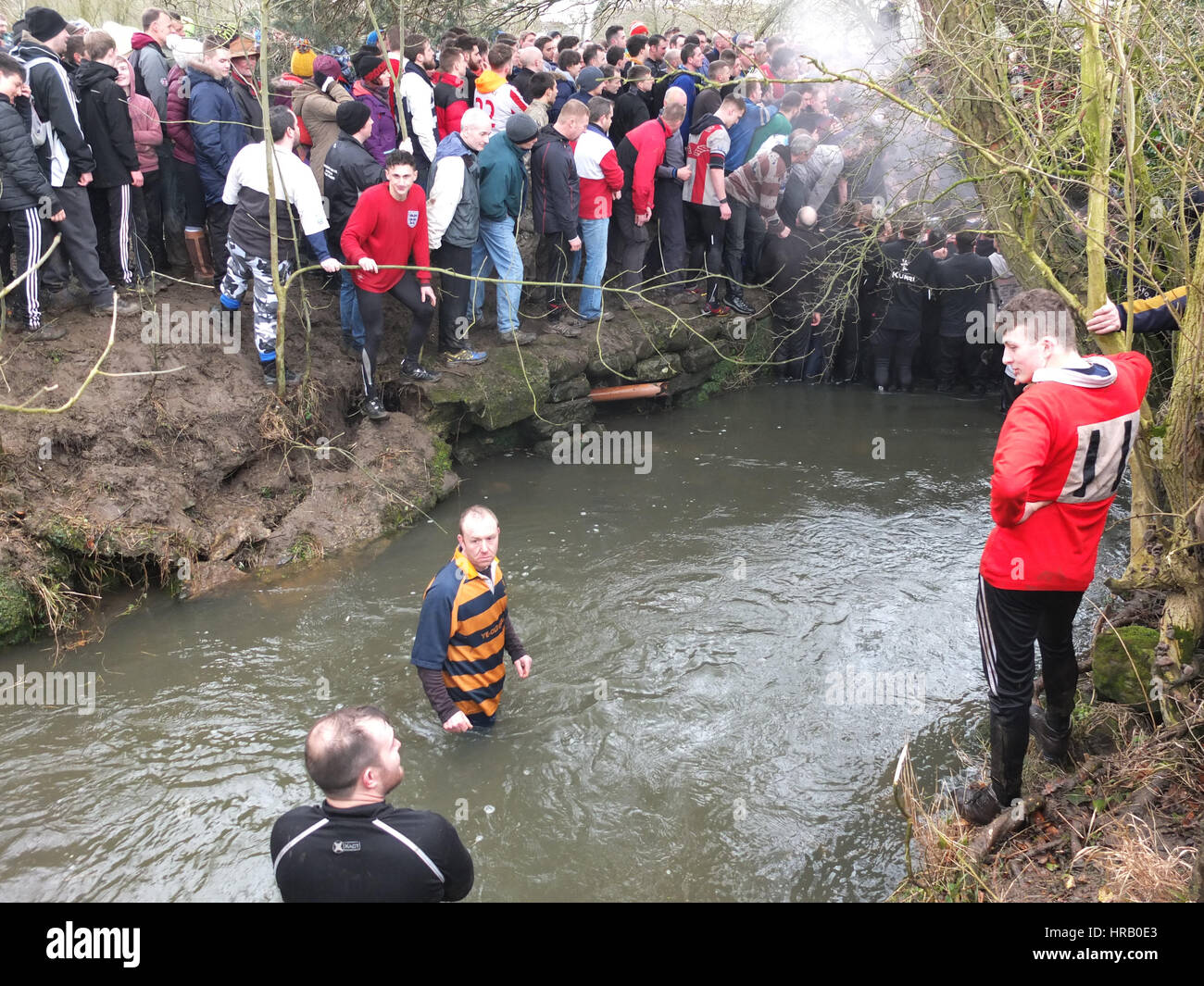 Ashbourne, Derbyshire, UK. The annual rumble between the Uppards and Downards that is Ashbourne Royal Shrovetide Footabll taking place. Essentially a giant rugby scrum that takes place over the whole town, players have to goal the ball at one of two goals and which team you play for depends on whether you were born upwards or downwards of the Henmore Brook which flocks through the town. The whole thing takes place again tomorrow (1st March), Ash Wednesday. Players in the Henmore Brook. Stock Photo