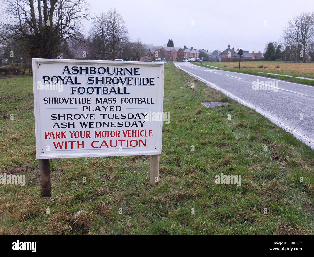 Ashbourne, Derbyshire, UK. The annual rumble between the Uppards and Downards that is Ashbourne Royal Shrovetide Footabll taking place. Essentially a giant rugby scrum that takes place over the whole town, players have to goal the ball at one of two goals and which team you play for depends on whether you were born upwards or downwards of the Henmore Brook which flocks through the town. The whole thing takes place again tomorrow (1st March), Ash Wednesday. Sign at approach to the historic market town advising drivers to park with caution. Stock Photo