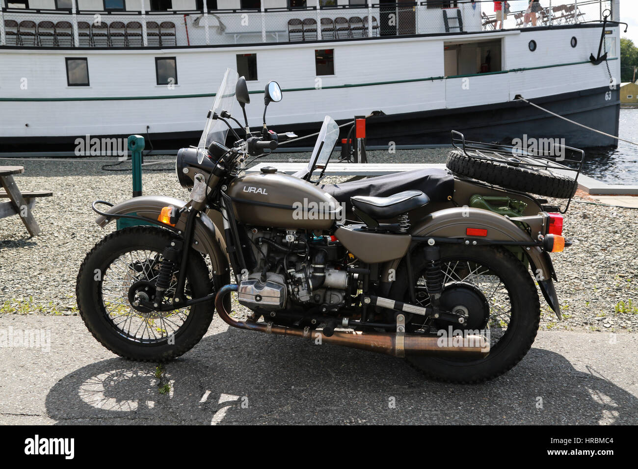 Russian-made motorcycle and in background The Century-old Motor Vessel Katahdin on Moosehead Lake docked in Greenville, Maine Stock Photo