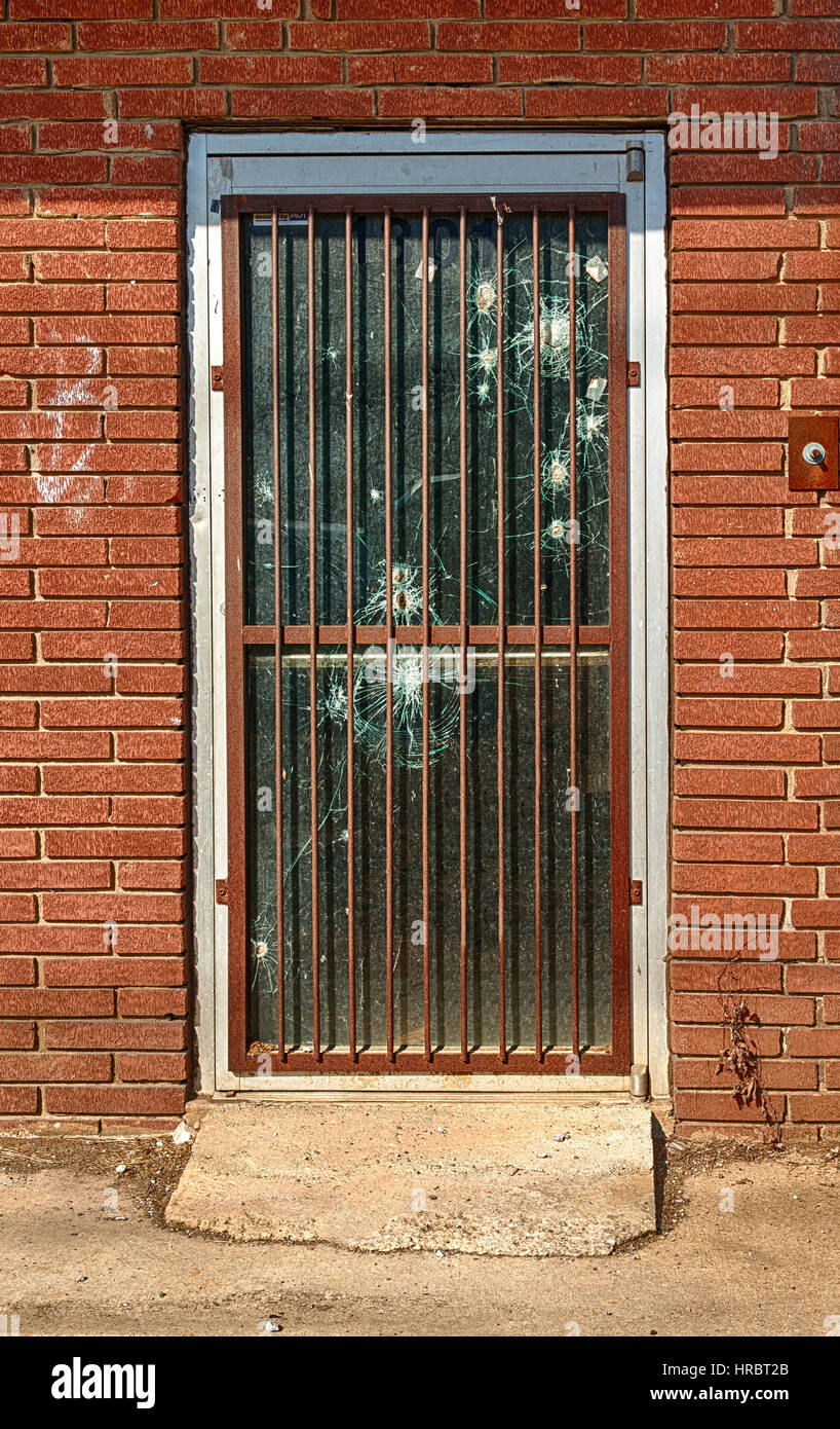The bars and bullet holes in the door of this abandoned business in an economically distressed area of Tennessee illustrates high-crime and danger. Stock Photo