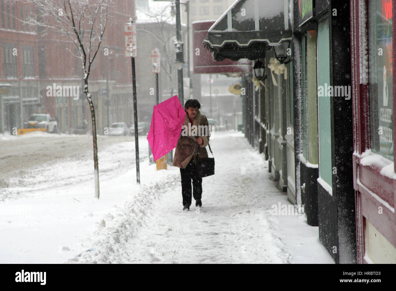 Snowstorm downtown Portland Maine woman walking sidewalk winter storm snow New England USA weather cold ice winter wind umbrella Stock Photo