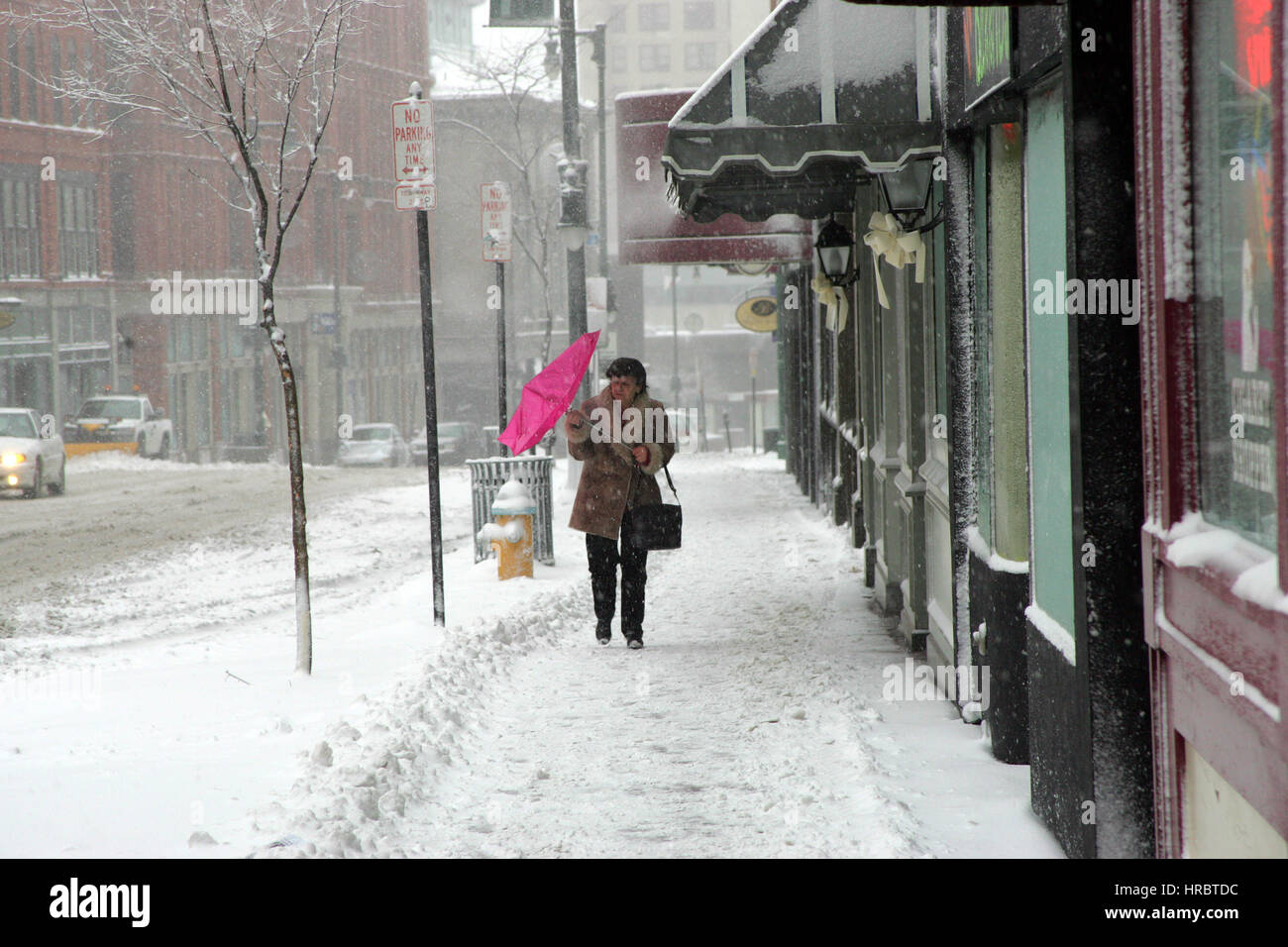 Snowstorm downtown Portland Maine woman walking sidewalk winter storm snow New England USA weather cold ice winter wind umbrella Stock Photo