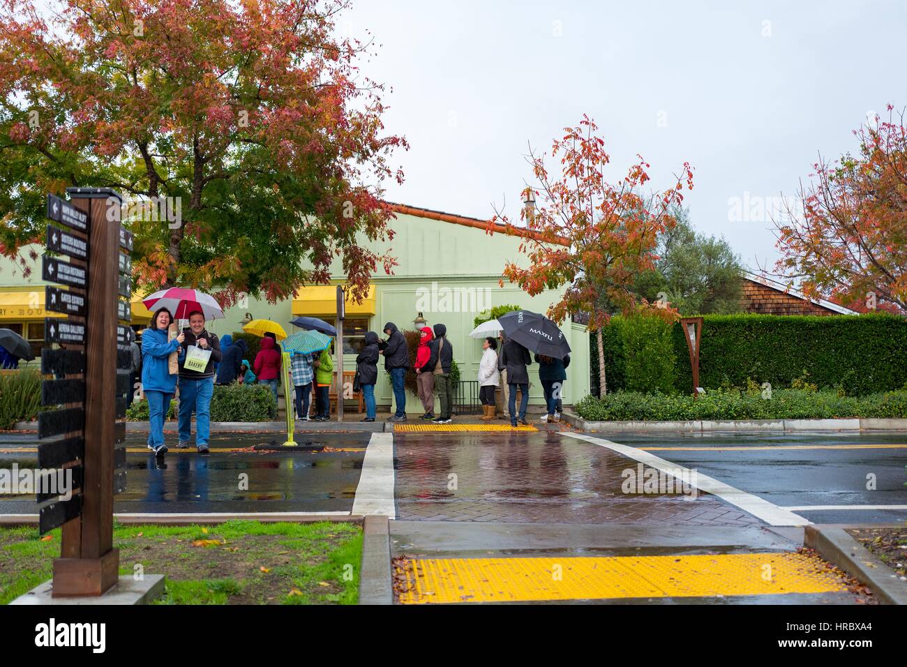 Tourists wait in the rain outside Bouchon Bakery in Yountville, Napa Valley, California, November 26, 2016. The restaurant, operated by chef Thomas Keller, is a popular spot for visitors to the Napa Valley. Stock Photo