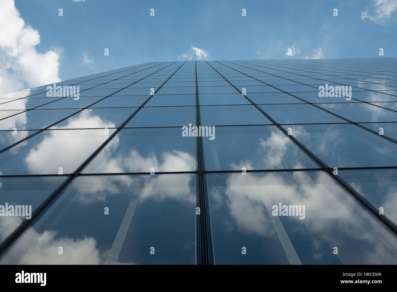 Glass facade of a modern office block reflecting the blue sky and white ...