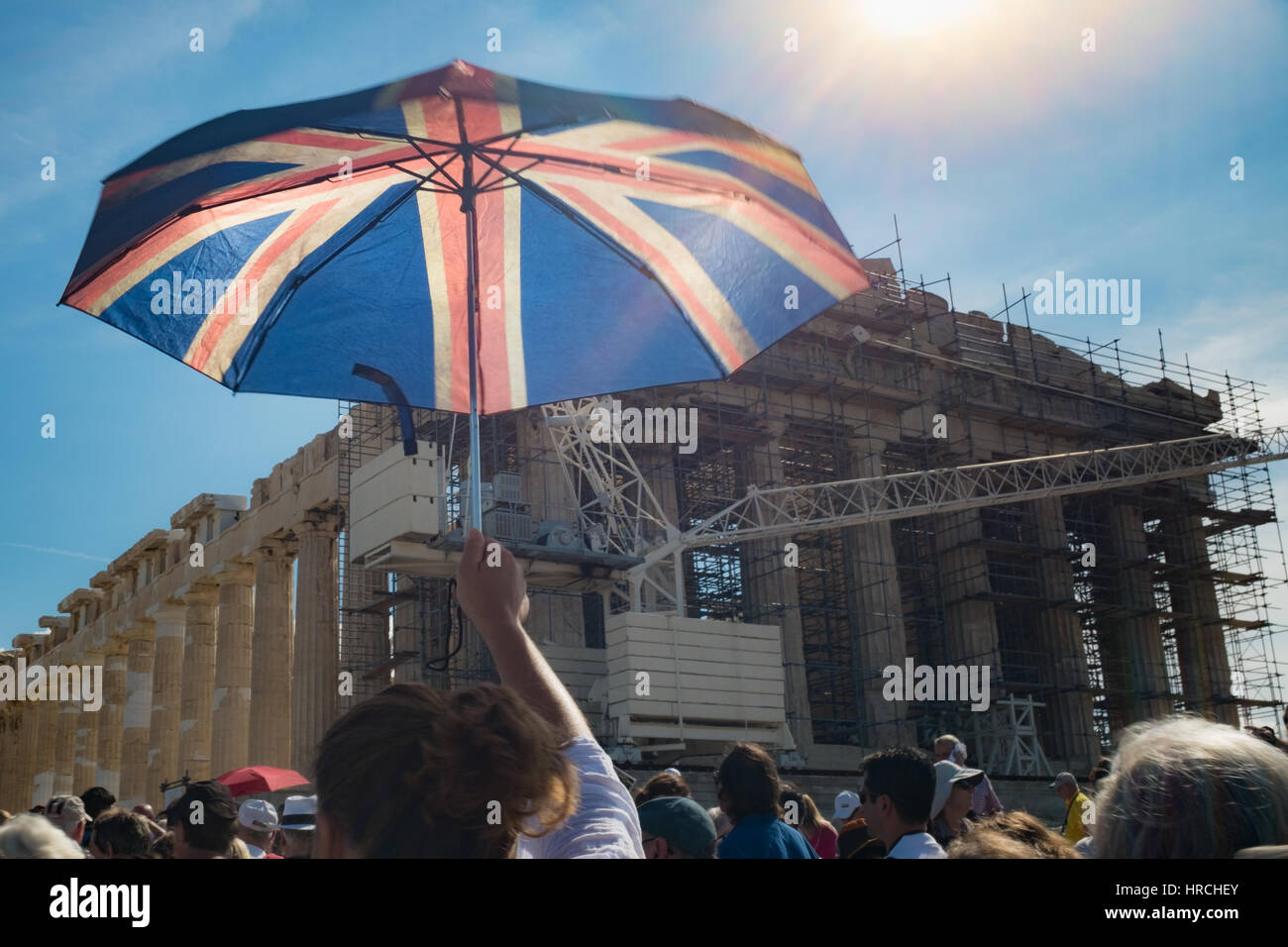 British or American tourist at the Acropolis, Athens, Greece opening a patriotic blue, white and red striped sunshade umbrella in a group of sightseer Stock Photo