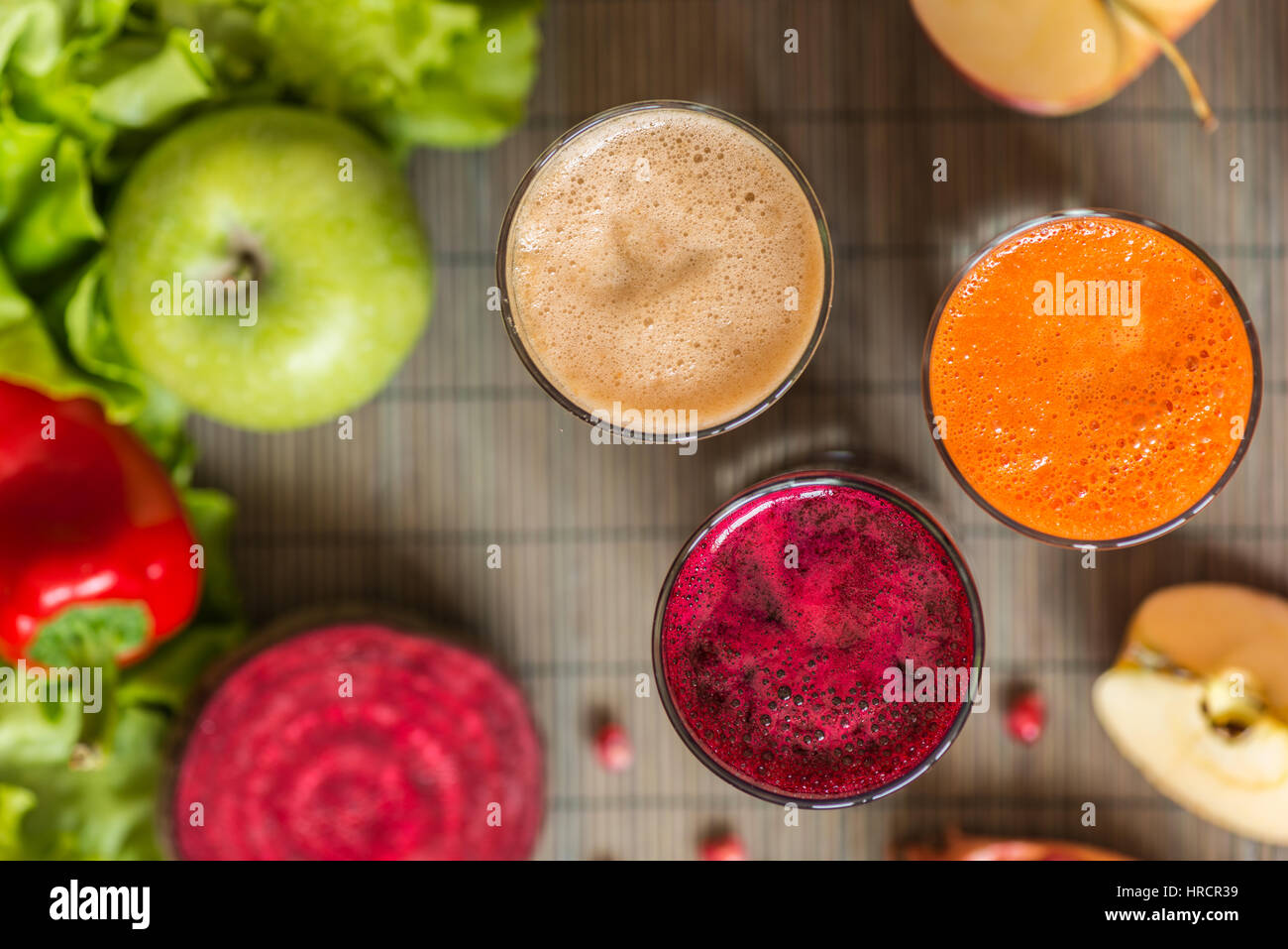 three glasses of different fresh juice. Beet, carrot and apple juices on grey wood background. Stock Photo