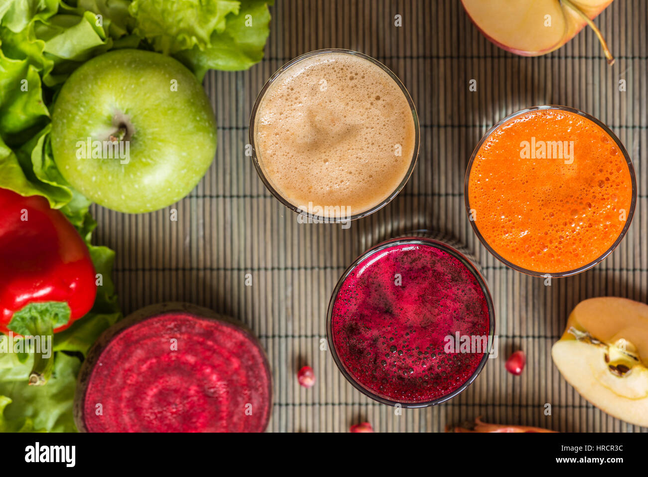 three glasses of different fresh juice. Beet, carrot and apple juices on grey wood background. Stock Photo