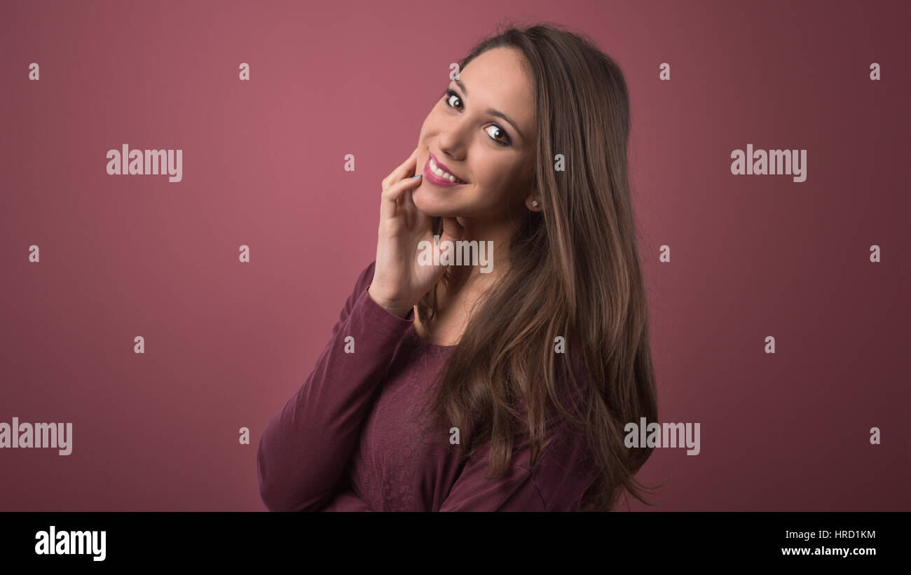 Beautiful young woman smiling and posing with hand on chin Stock Photo ...