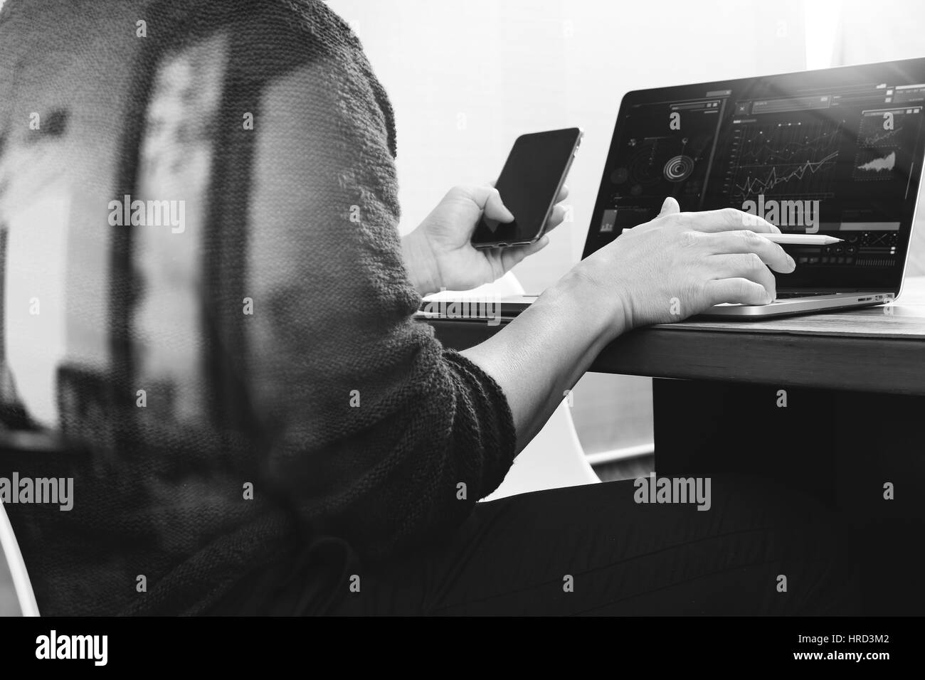 Designer hand using mobile payments online shopping,omni channel,laptop computer on wooden desk,black white Stock Photo