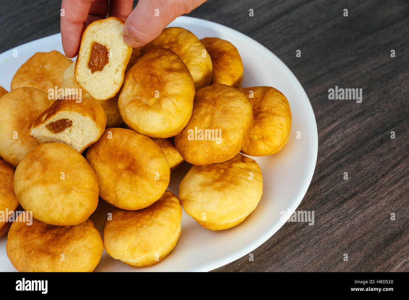 German donuts - berliner with jam and icing sugar in a tray on a dark wooden background. Stock Photo
