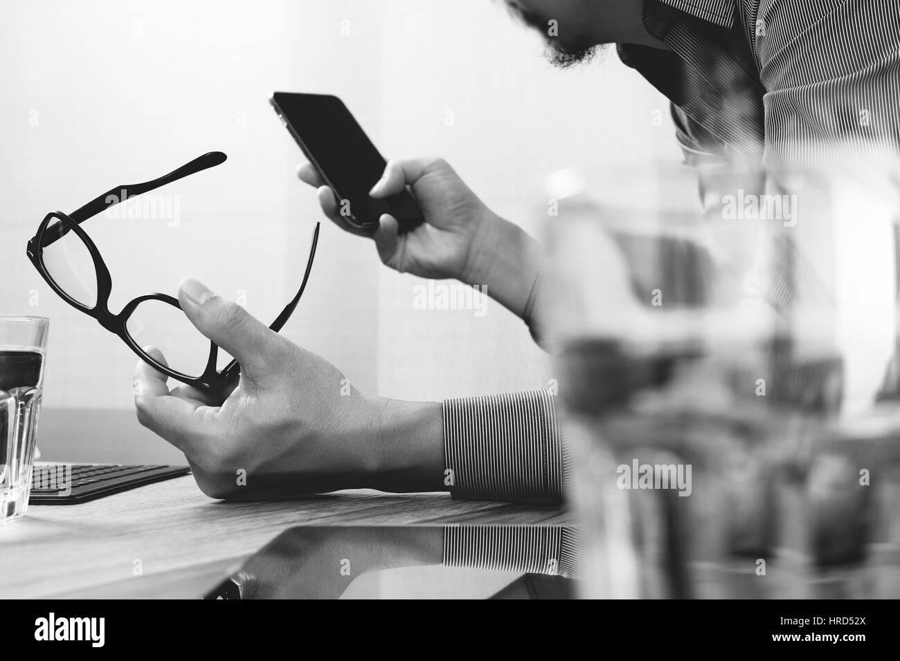 Businessman hand using mobile payments online shopping,omni channel,laptop computer on wooden desk,black white Stock Photo
