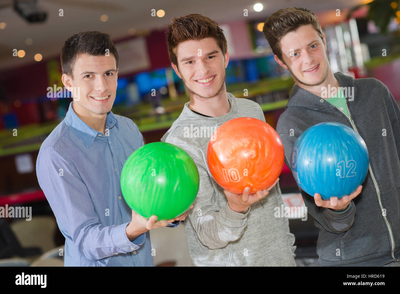Three men holding bowling balls Stock Photo Alamy