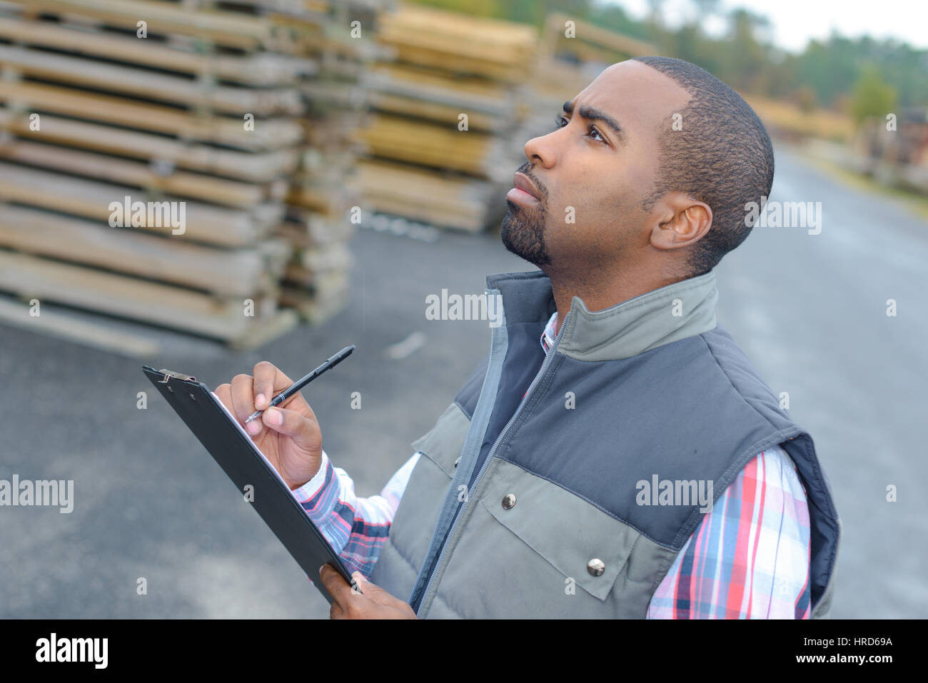 Man outdoors writing on clipboard Stock Photo - Alamy