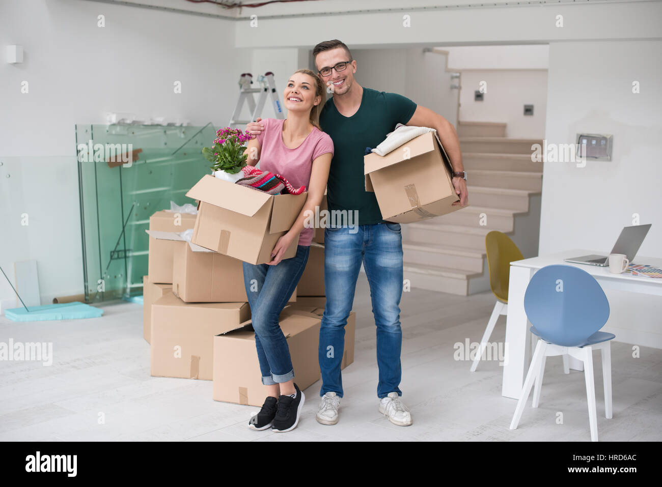 Happy young couple unpacking or packing boxes and moving into a new ...