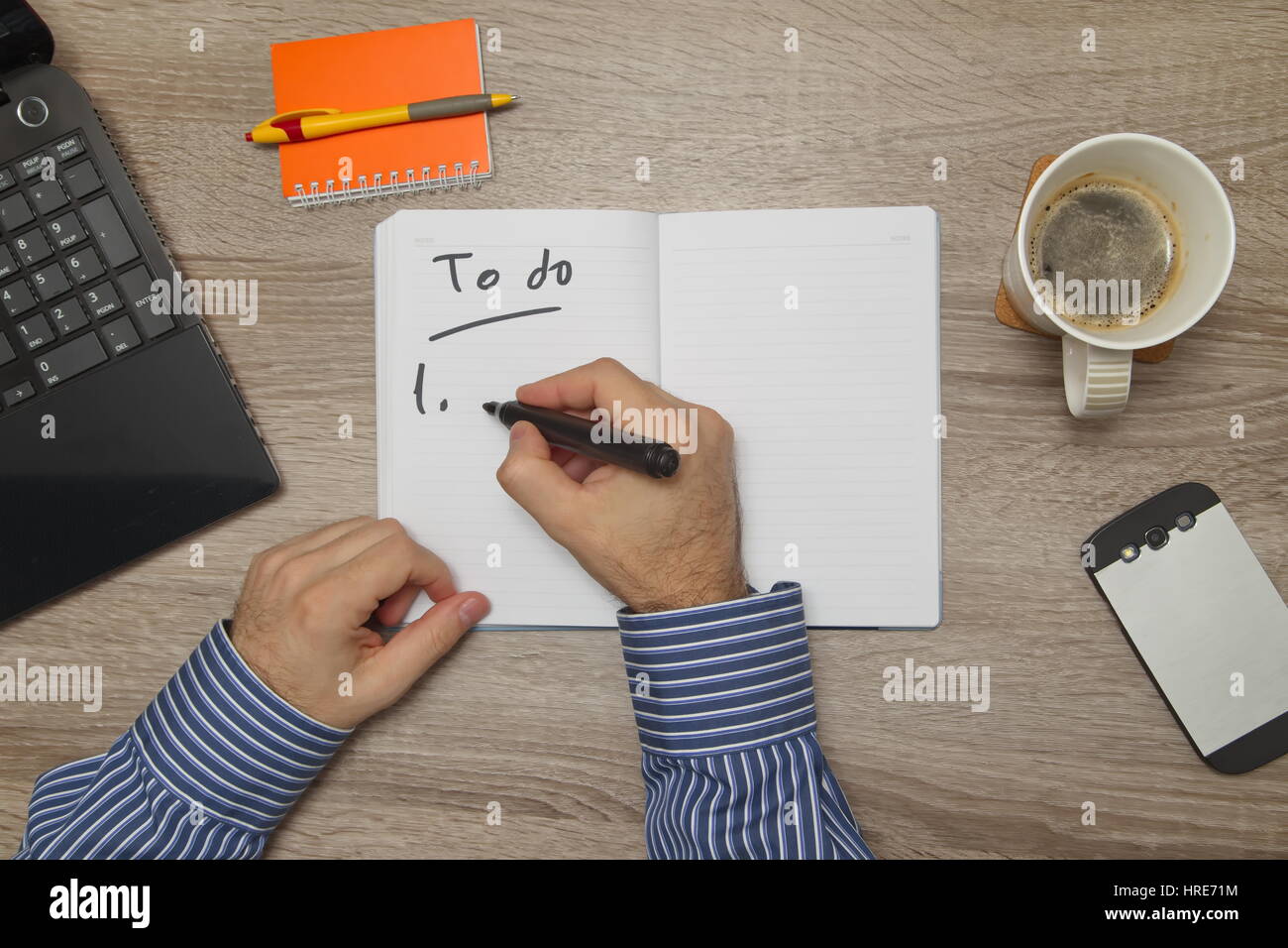 Male hand writing text ' to do' in notebook while as he drinks coffee Stock Photo