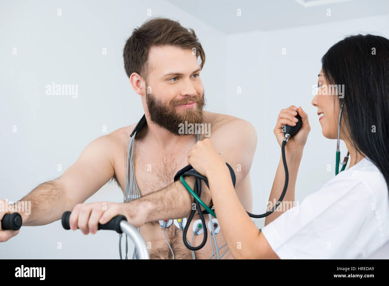 Female doctor measuring blood pressure of male patient cycling with