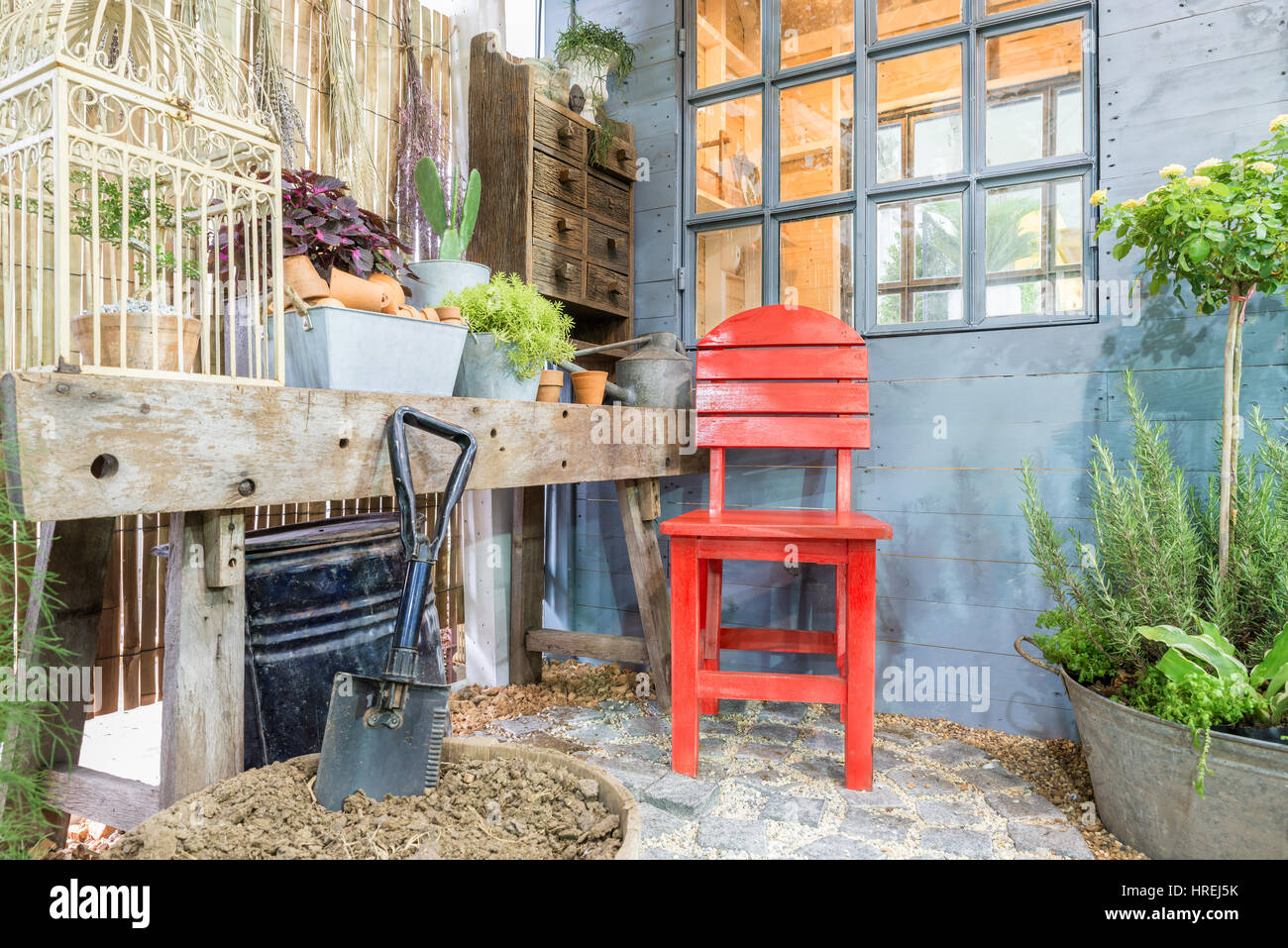 Red chair at green garden with cosy house. Outdoor garden. Stock Photo