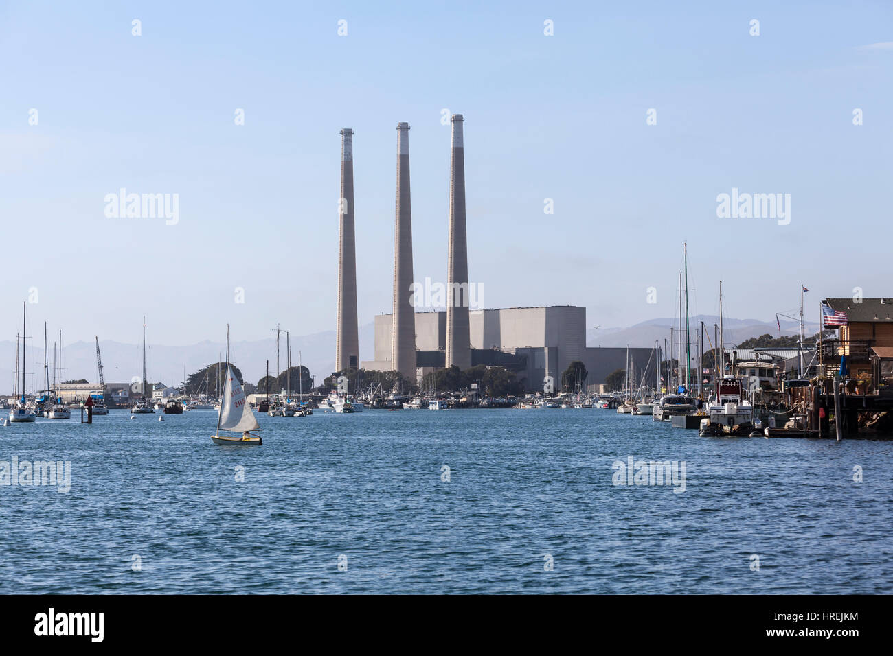 Morro Bay, California, USA - July 6, 2014:  Recreational boats moored below towering 450 foot smokestacks of the recently closed power plant in Morro  Stock Photo