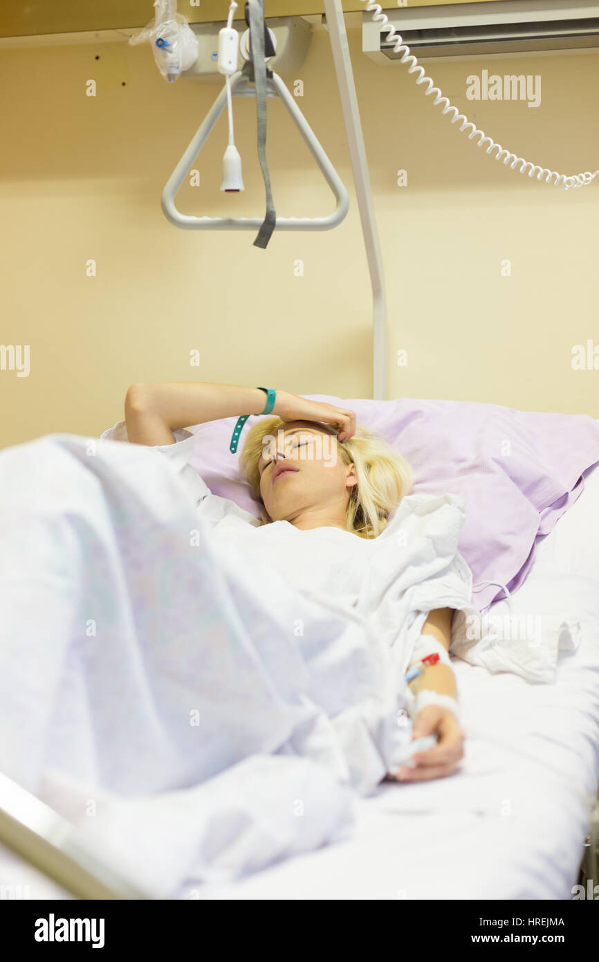 Bedridden female patient lying in hospital bed, recovering after