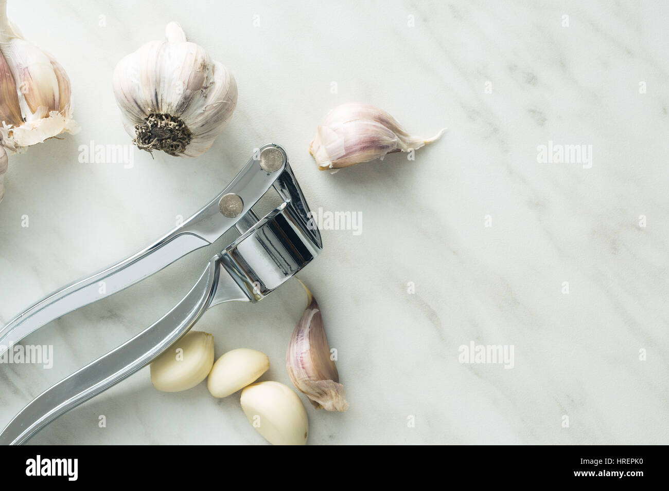 Garlic and garlic press on kitchen table. Top view. Stock Photo