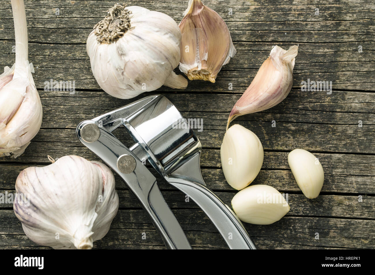 Garlic and garlic press on old wooden table. Top view. Stock Photo