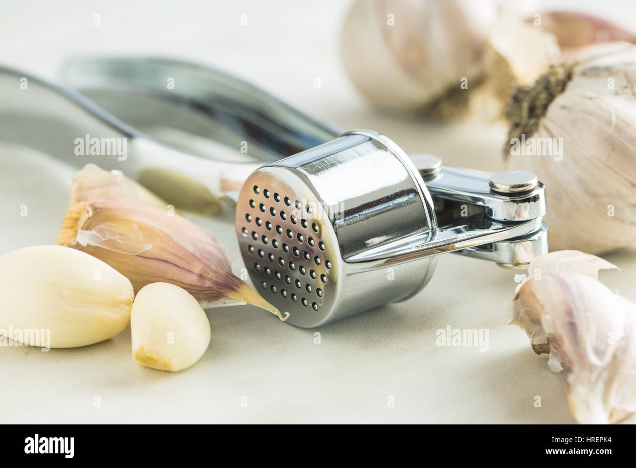 Garlic and garlic press on kitchen table. Stock Photo