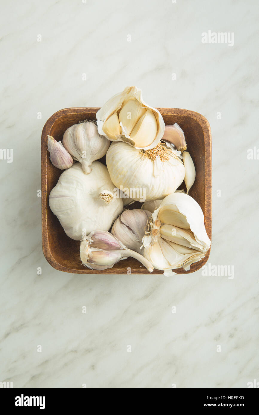 Fresh garlic in wooden bowl on kitchen table. Top view. Stock Photo