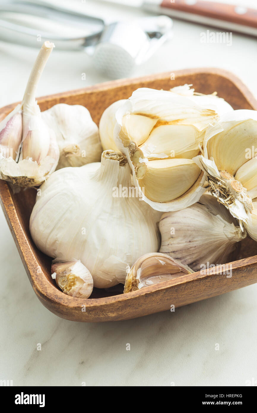 Fresh garlic in wooden bowl on kitchen table. Stock Photo