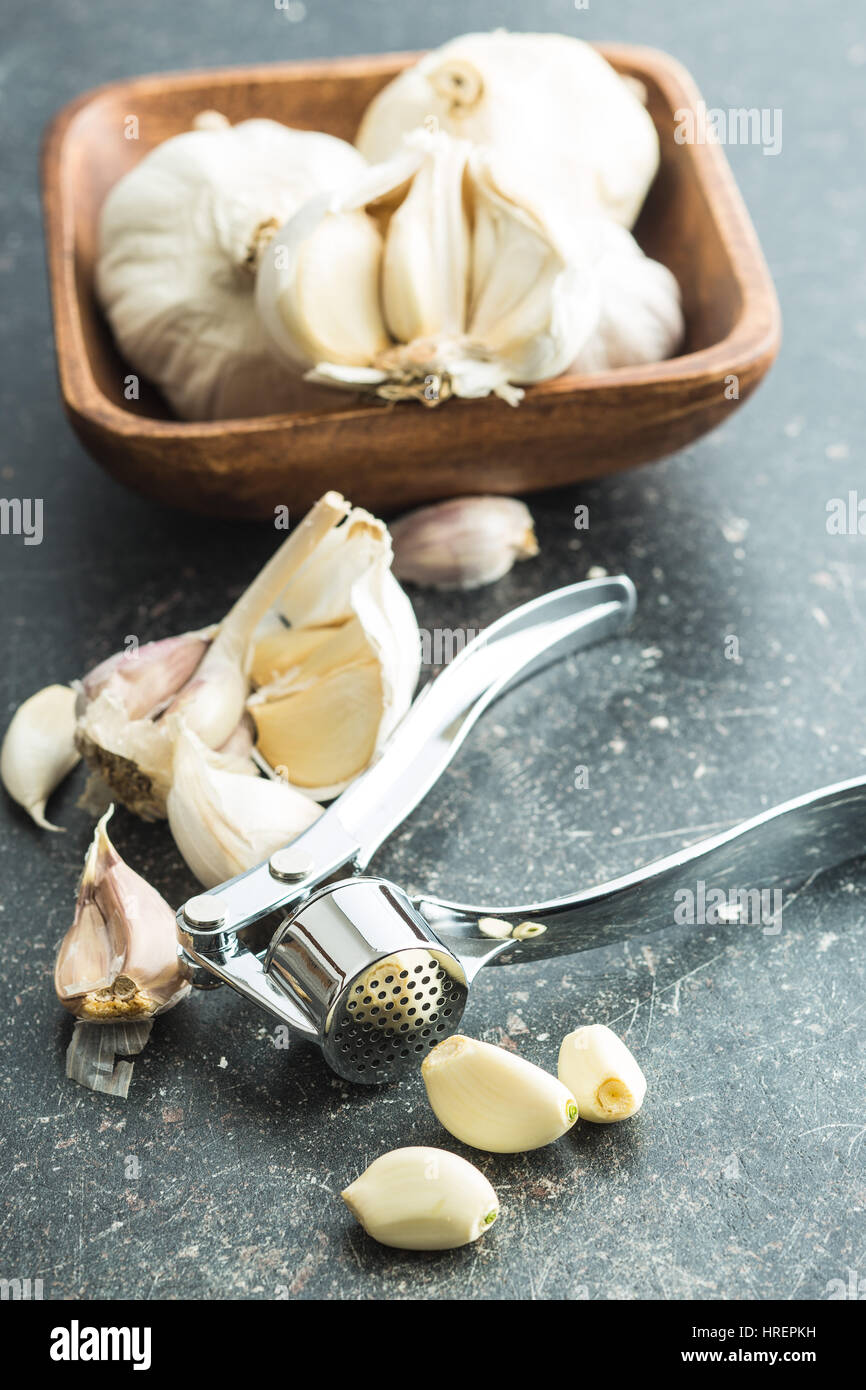 Garlic and garlic press on kitchen table. Stock Photo