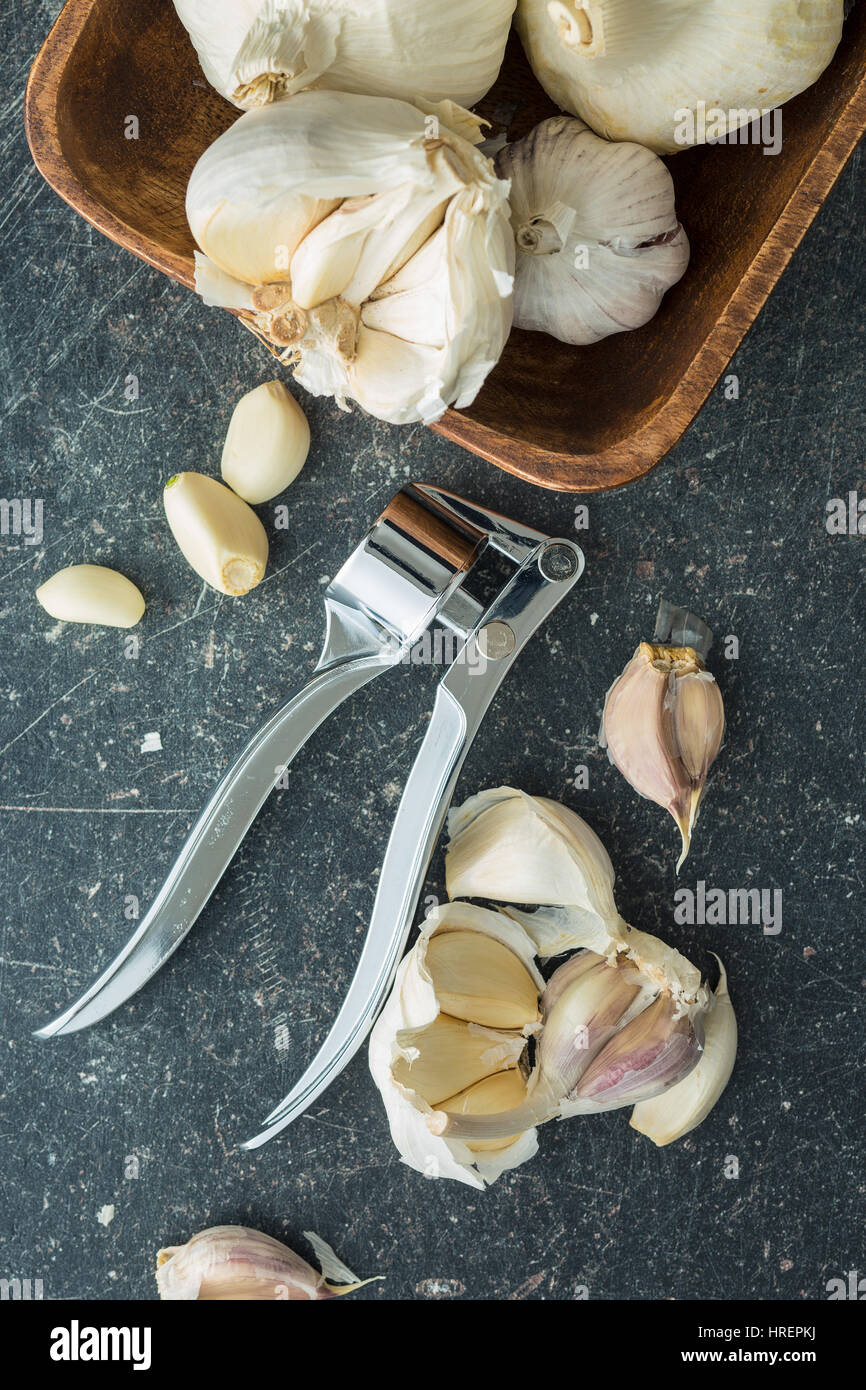 Garlic and garlic press on kitchen table. Top view. Stock Photo