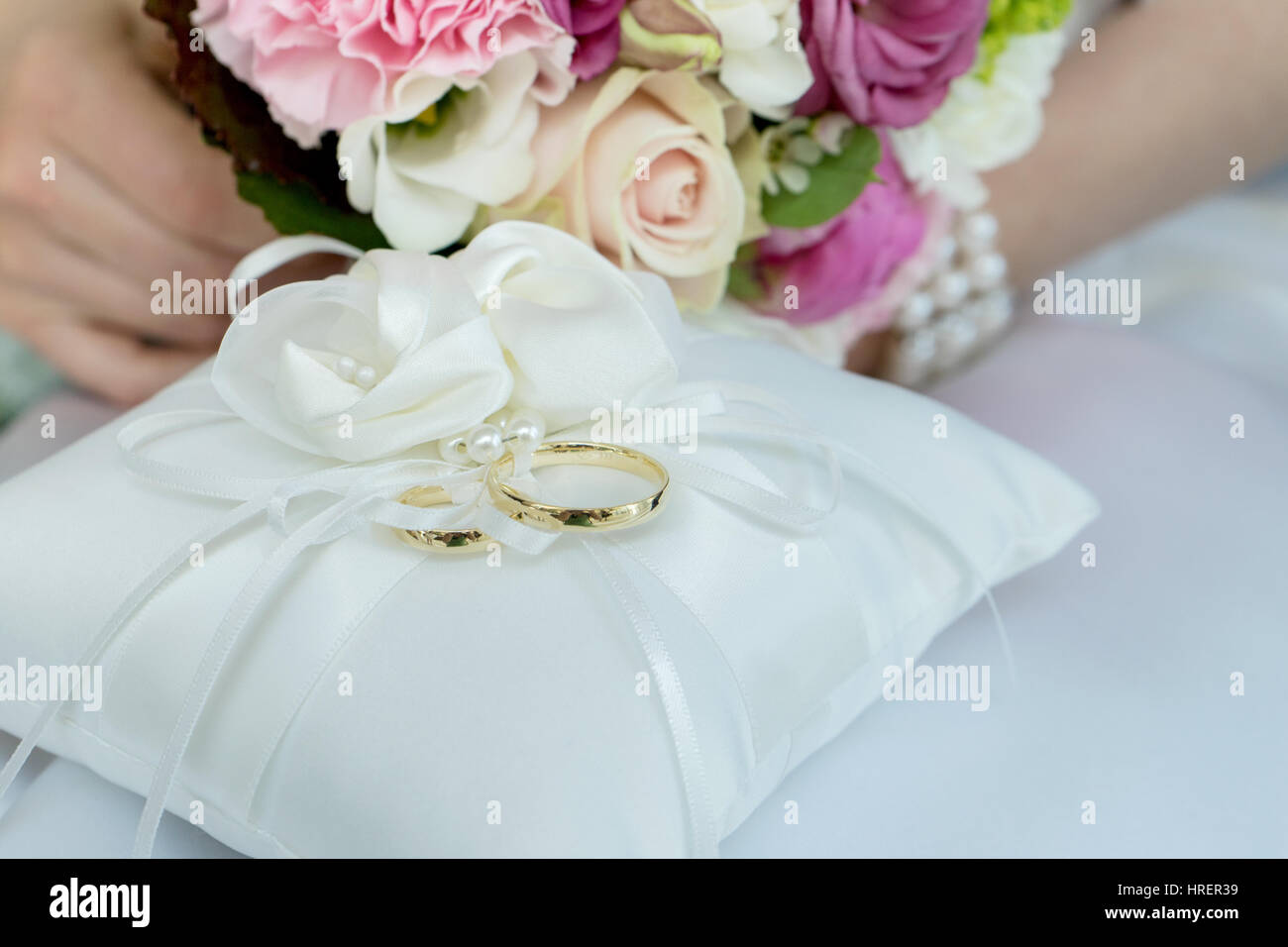 white cushion with two golden wedding rings Stock Photo