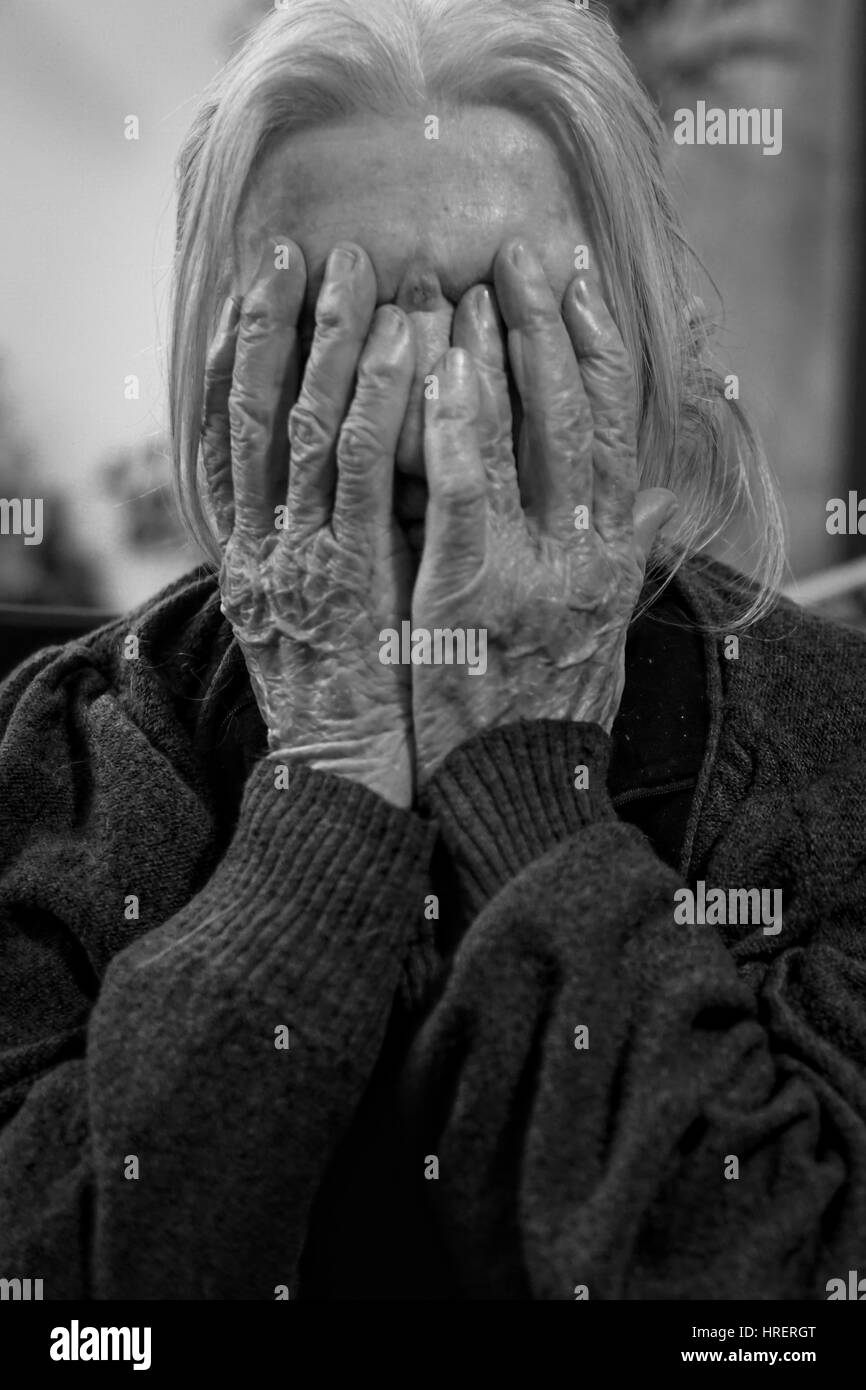 Elderly woman hiding her face behind her hands. Stock Photo