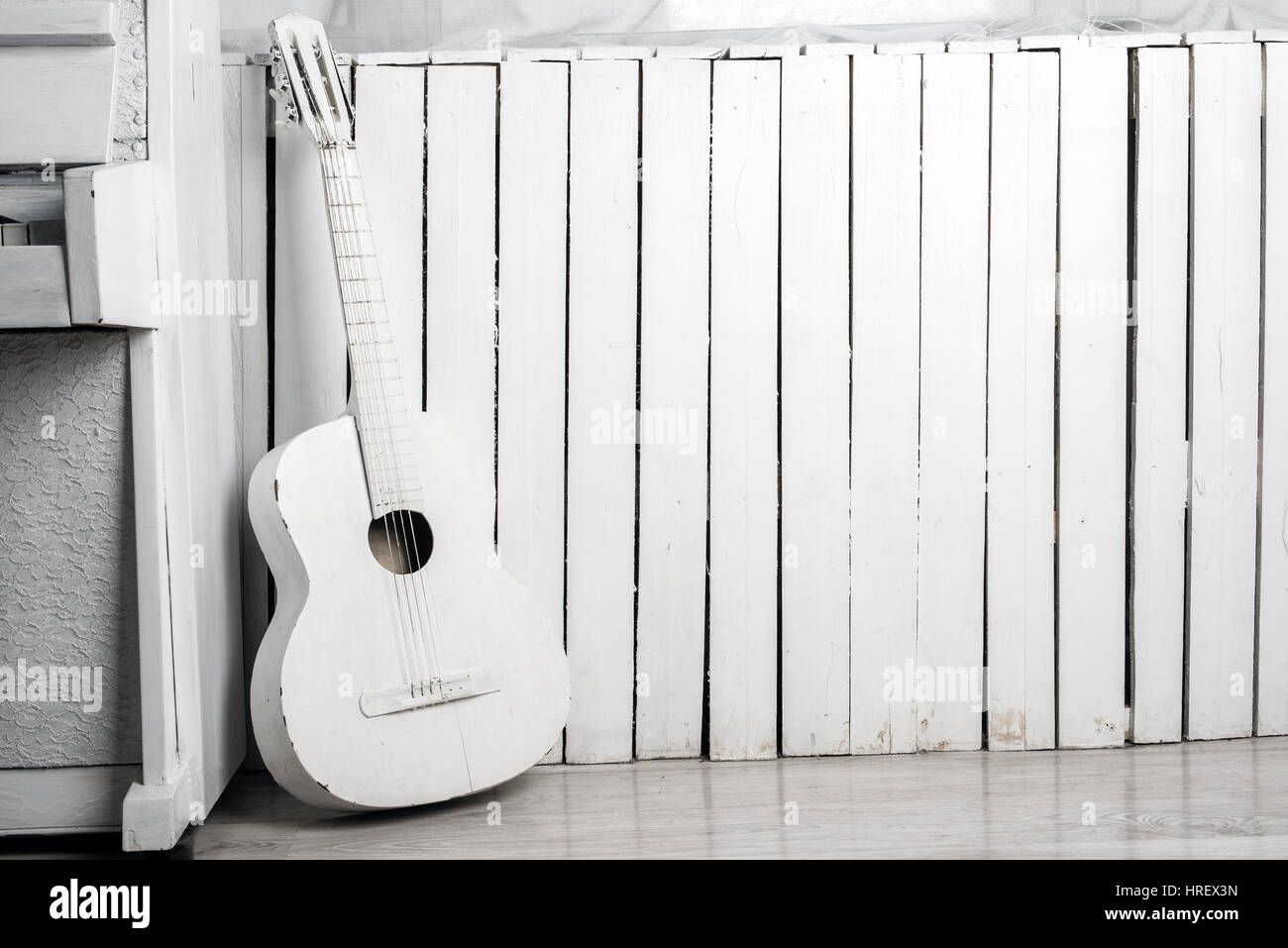 Old acoustic guitar leaning against the white wooden wall Stock Photo -  Alamy