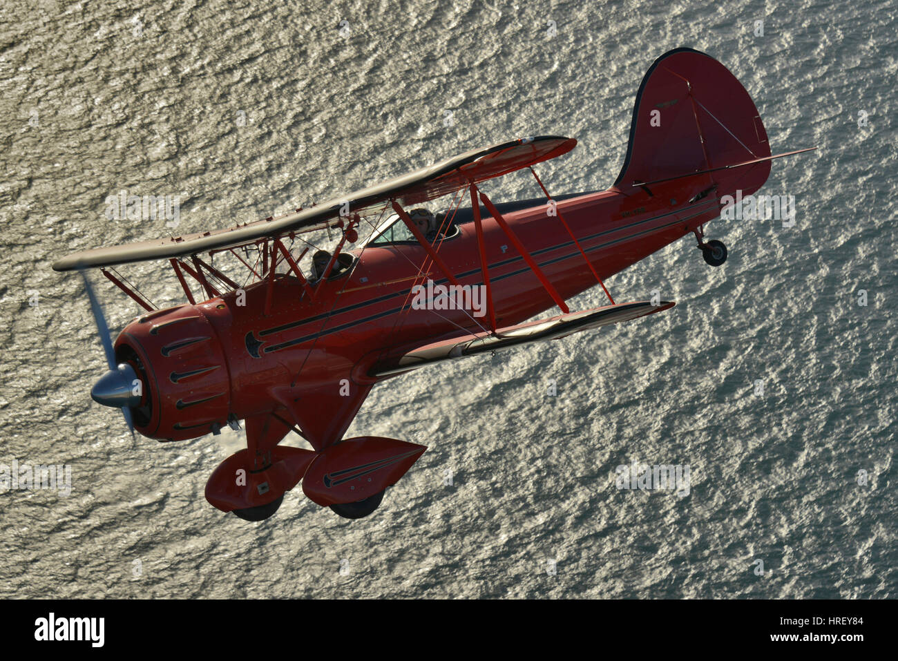 An air to air portrait of a Red Waco YMF-F5C biplane over the ocean, Western Australia. Stock Photo