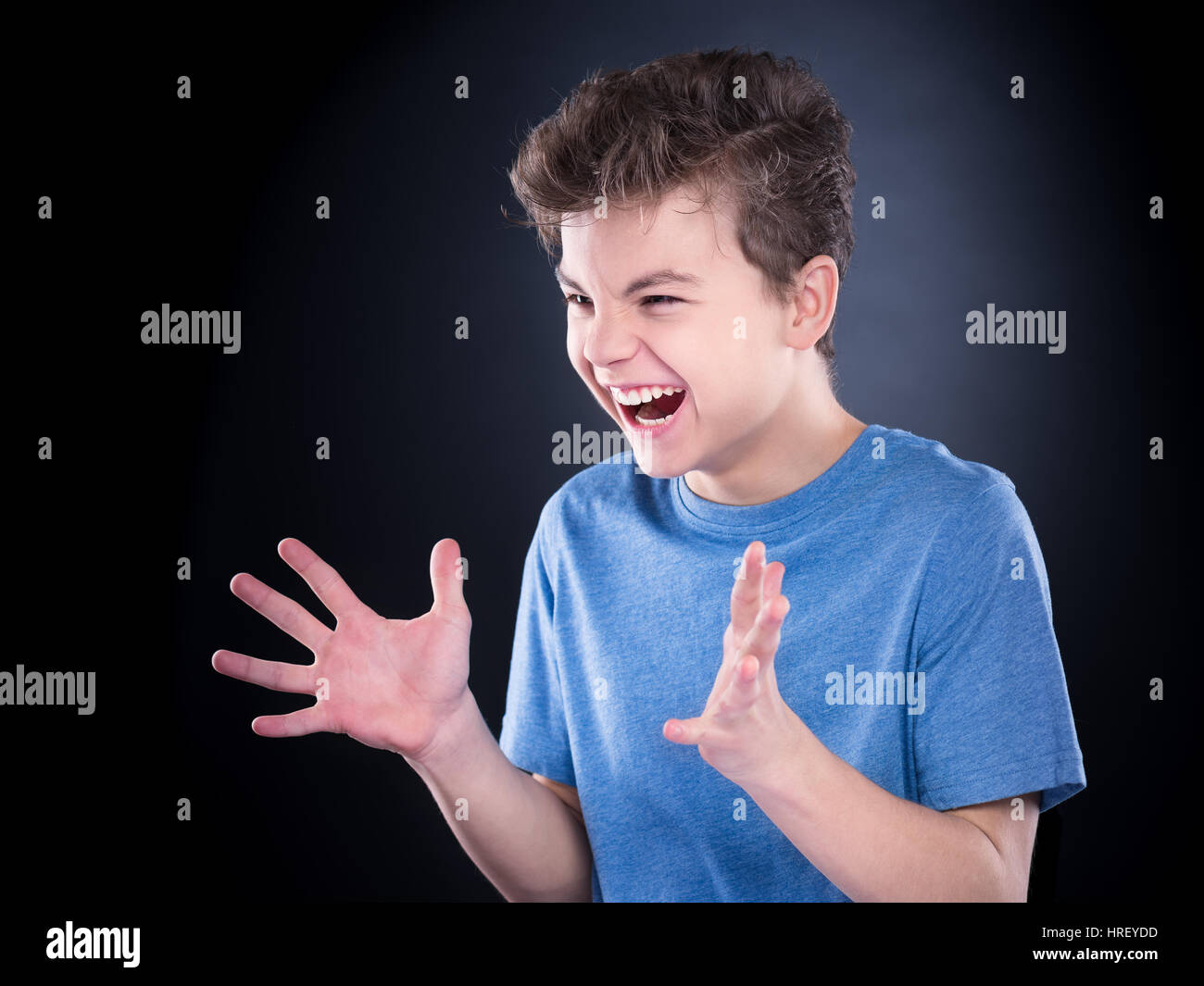 Emotional portrait of irritated shouting teen boy. Furious teenager screaming and looking with anger away. Handsome outraged child shouting out loud,  Stock Photo