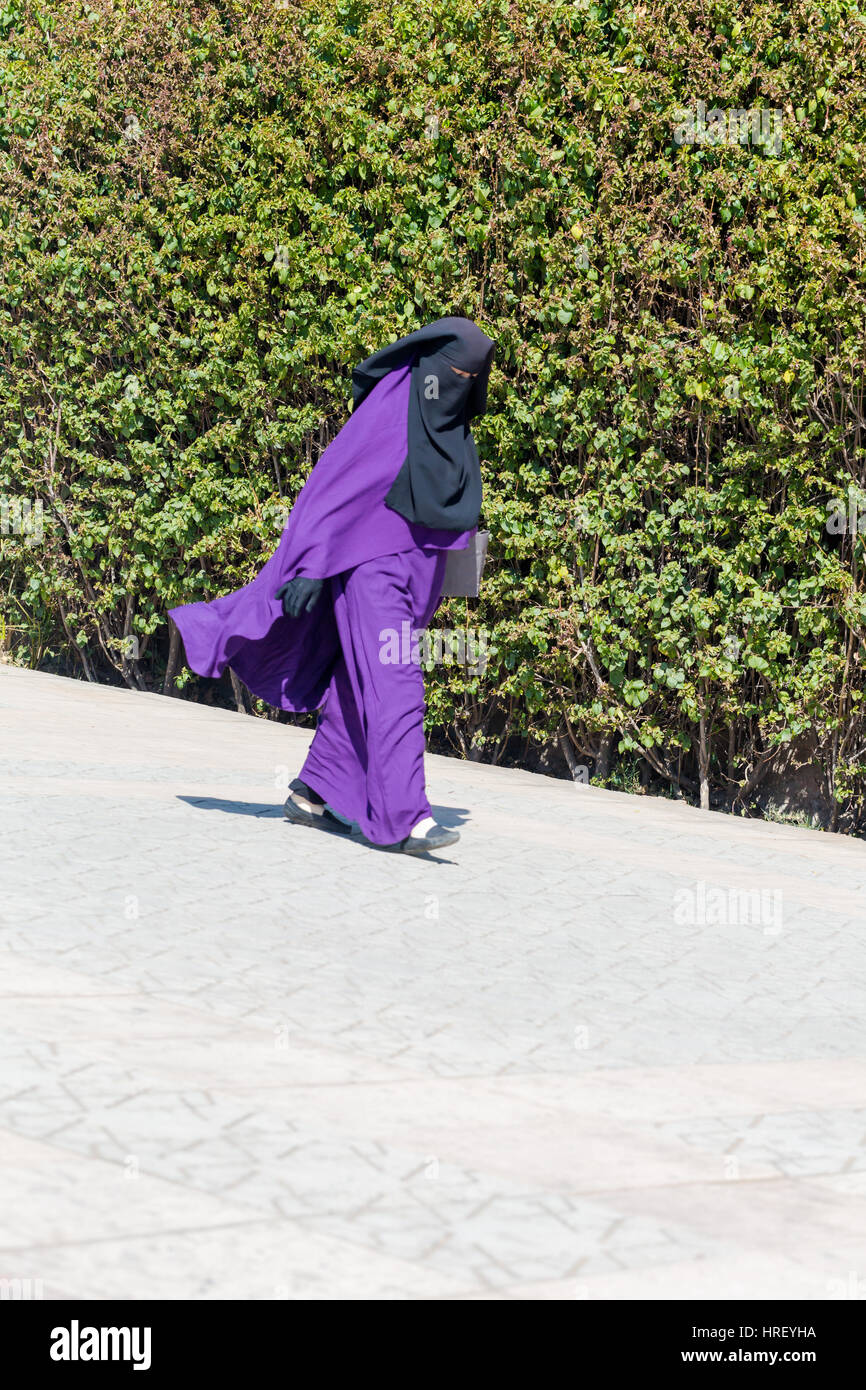 Islamic Muslim woman wearing violet black Niqab walks on Marrakesh street. Vertical shot. 15 February 2017 Stock Photo