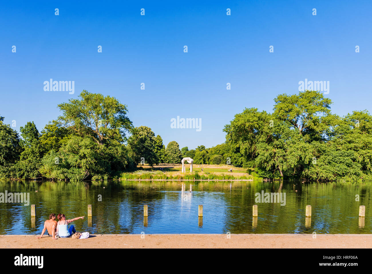 LONDON - JULY 19:  Couple is sitting by a lake in Hyde park with their feet in the water on a hot sunny day on July 19, 2016 in London Stock Photo