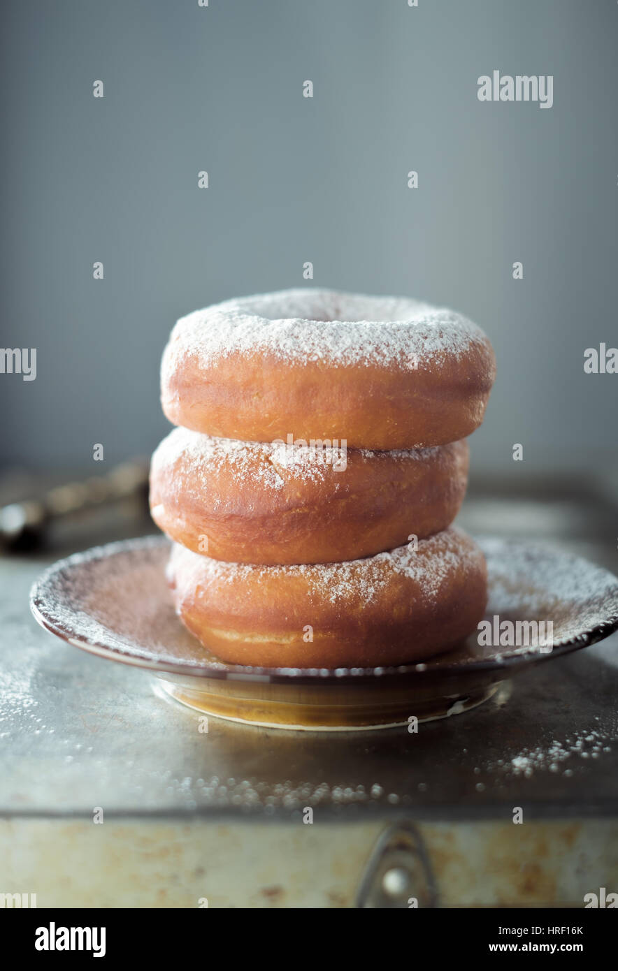 Delicious Donuts on plate stacked up against pastel background Stock Photo