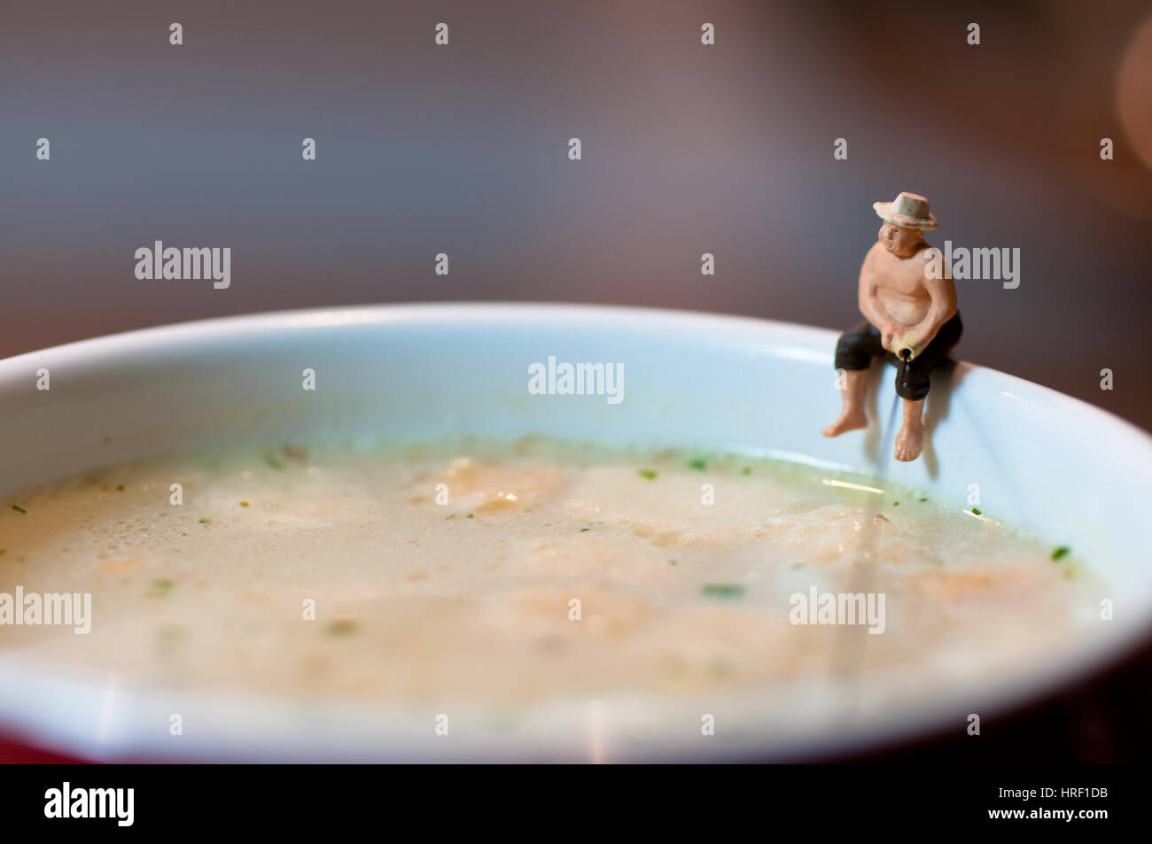 Tiny fisherman fishing in a soup mug.. Macro photo Stock Photo