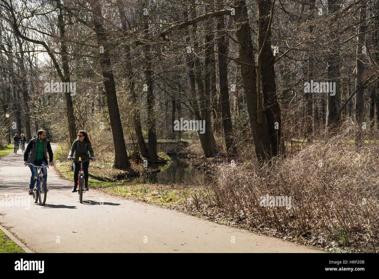 A young couple cycling in a park on a cold day. Tiergarten, Berlin, Germany Stock Photo