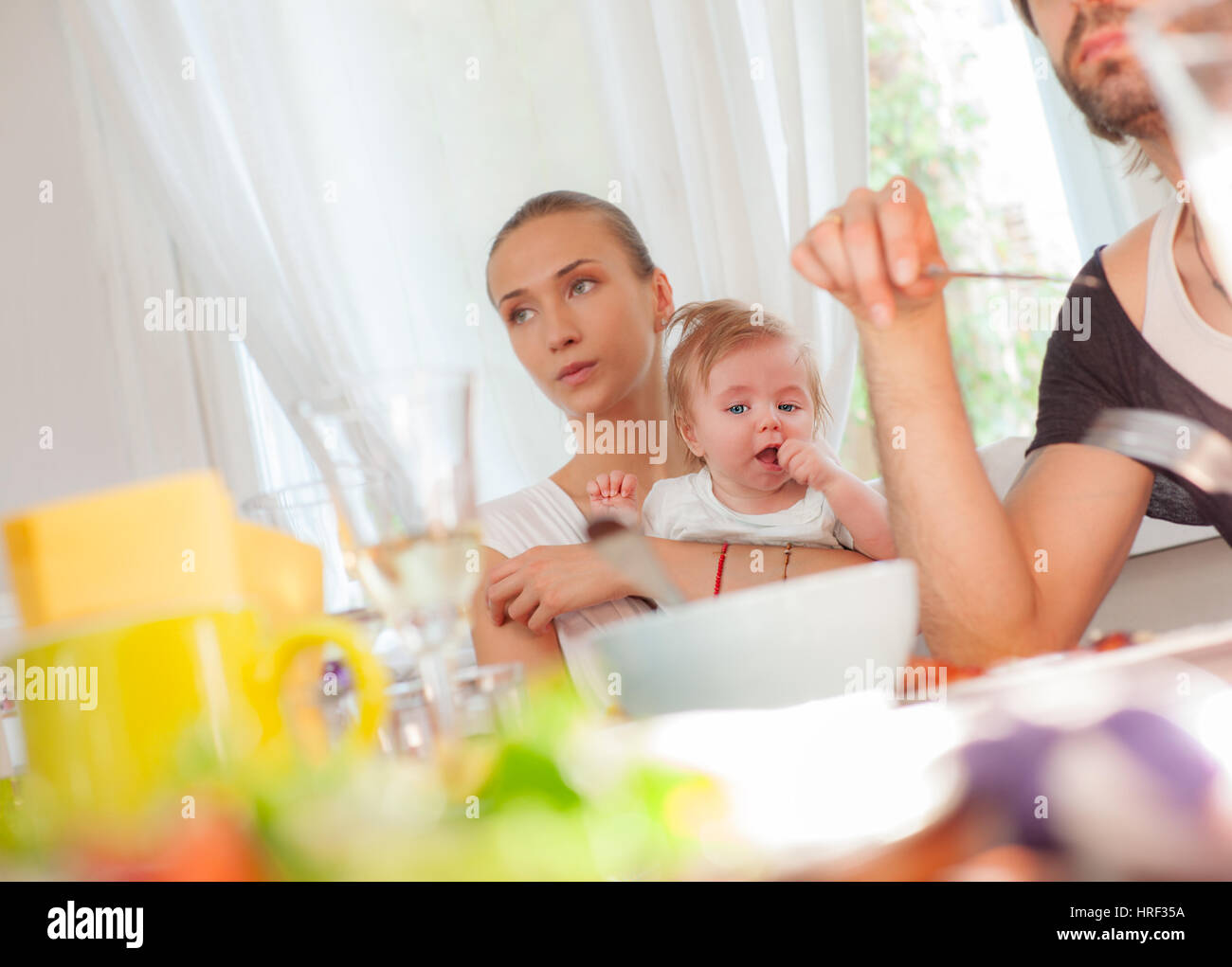 A little baby boy is held by his mother in restaurant during a family lunch. Stock Photo