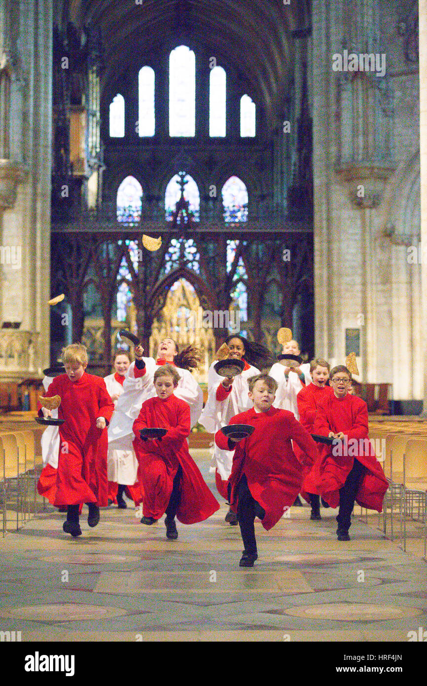 The girl and boy choristers practising on Monday morning (Feb 27) at Ely Cathedral in Cambridgeshire for tomorrows Shrove Tuesday pancake race held in the cathedral.  Choristers have been practising for the traditional pancake race at Ely Cathedral in Cambridgeshire tomorrow (Tues).  The resident choristers wore their red and white cassocks as they flipped pancakes to mark Shrove Tuesday.  The boys and girls spent around an hour perfecting their pancake tossing skills for the annual event.  Each year around 20 choristers race down the nave of the 12th Century Cathedral after Evensong. Stock Photo