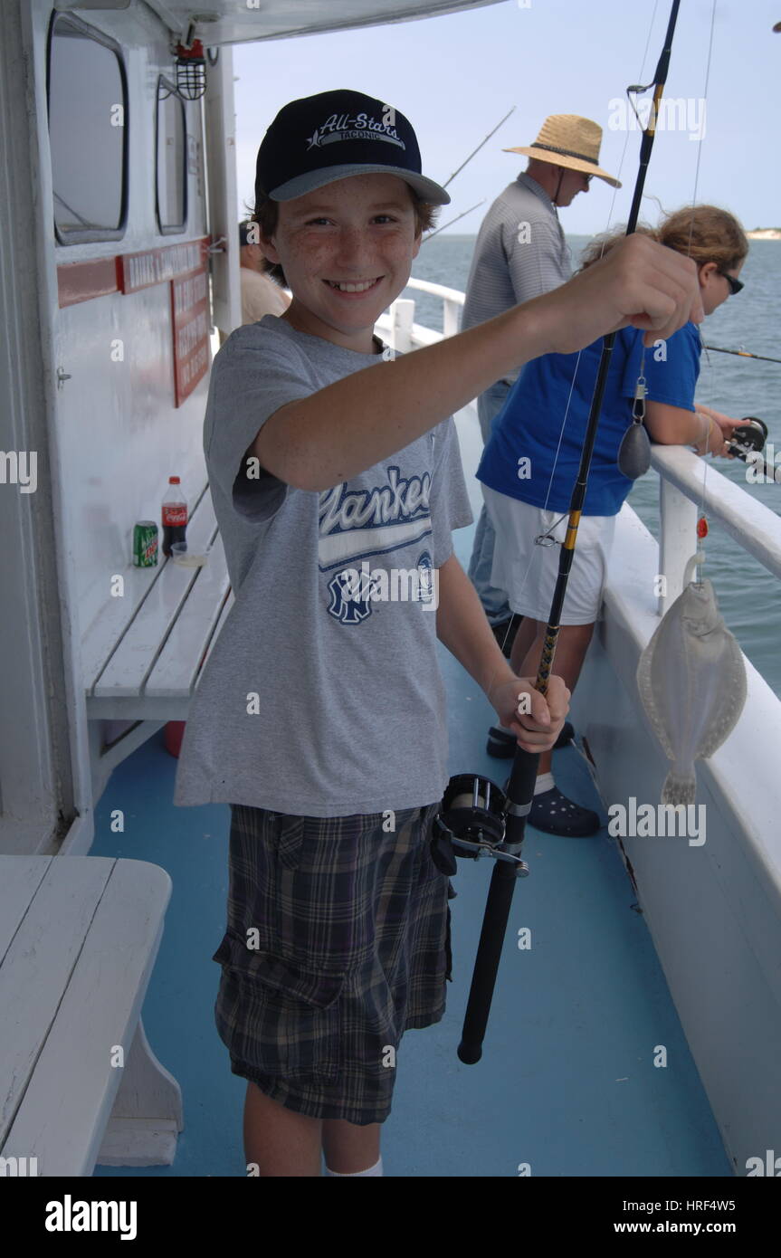 Happy boy child catches a fish on fishing party boat, Outer Banks