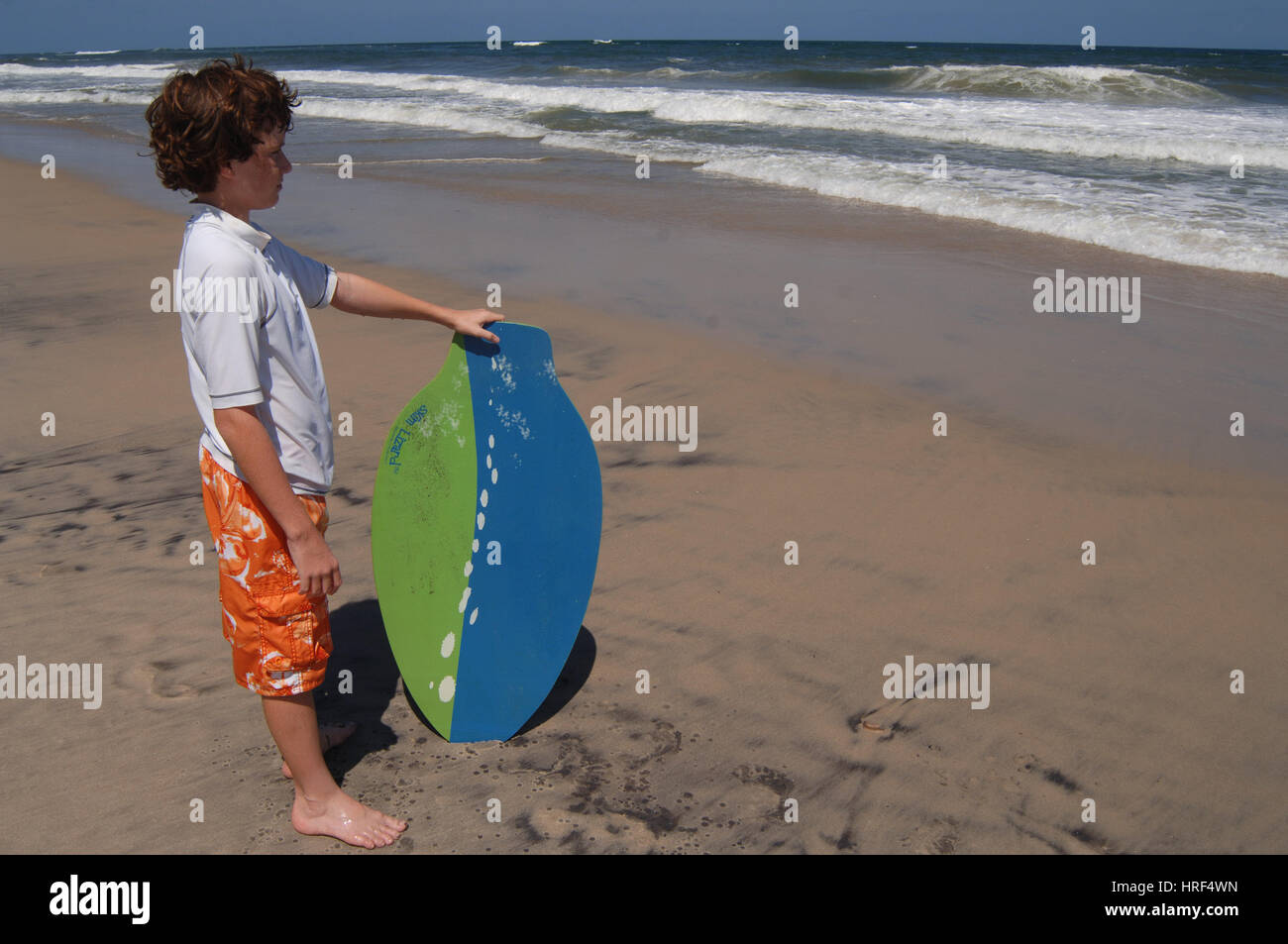 Boy child riding skim board in ocean surf on summer vacation Stock
