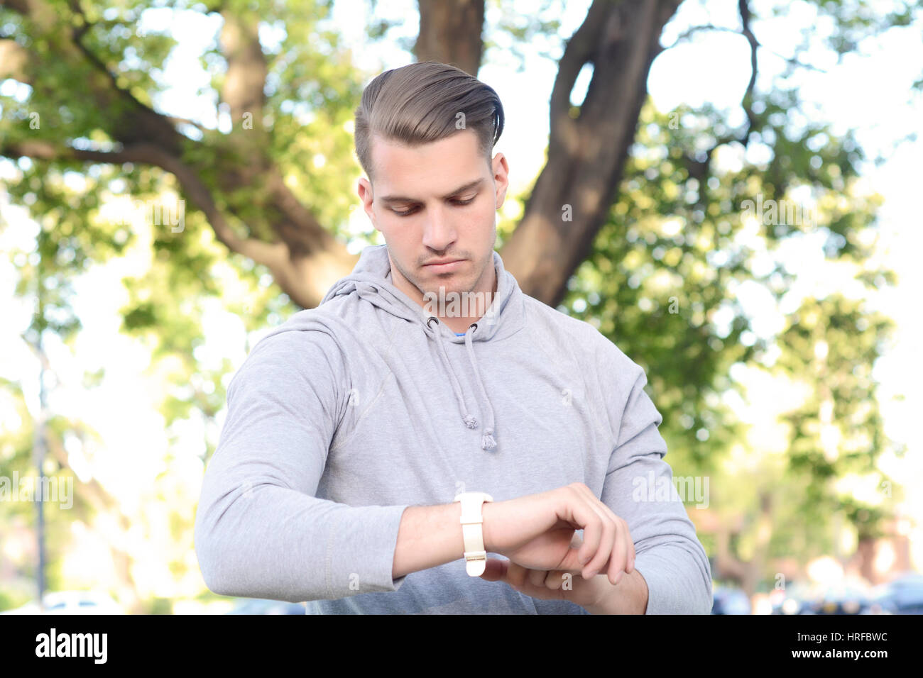 Portrait of young latin man looking at his watch at park. Outdoors. Stock Photo
